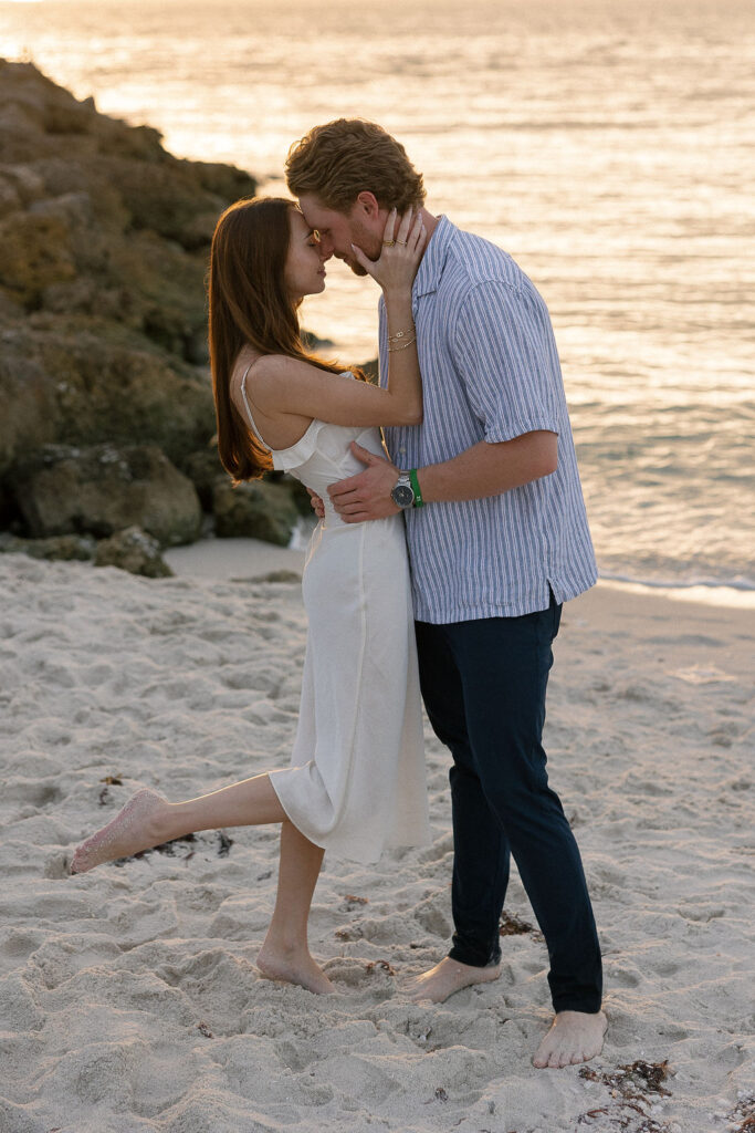 Engagement photos Naples Florida with couple standing by the ocean waves in the sand.