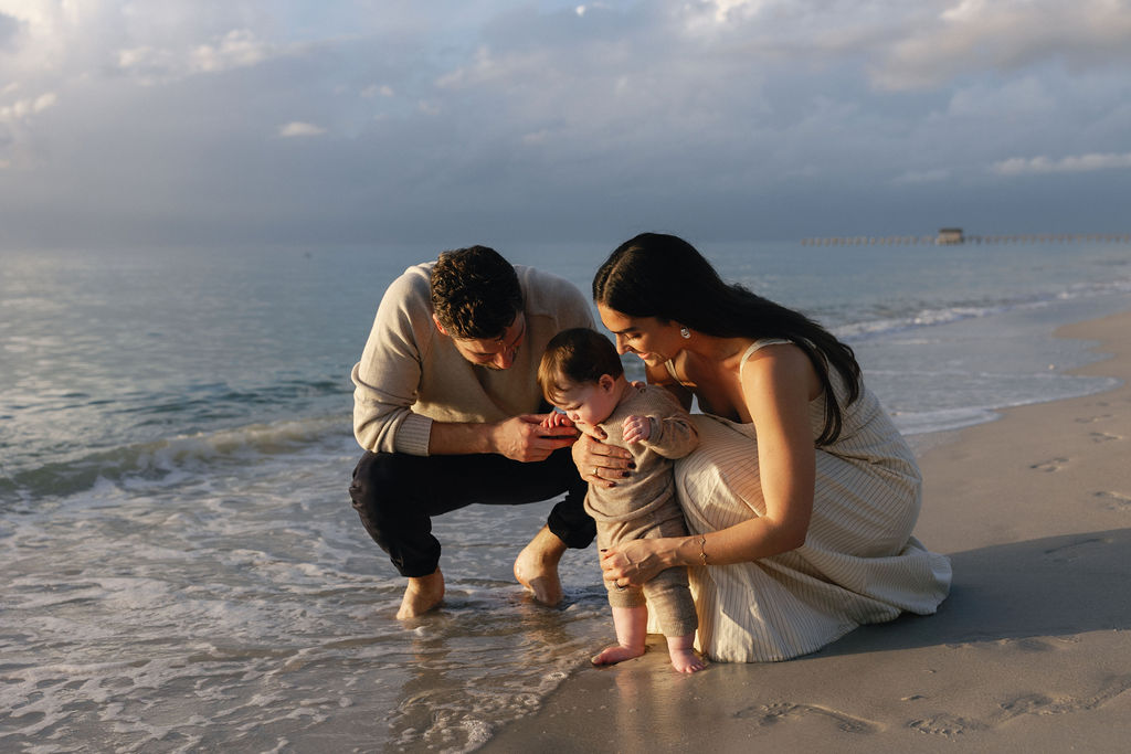 Parents and child with feet in water together in natural candid pose