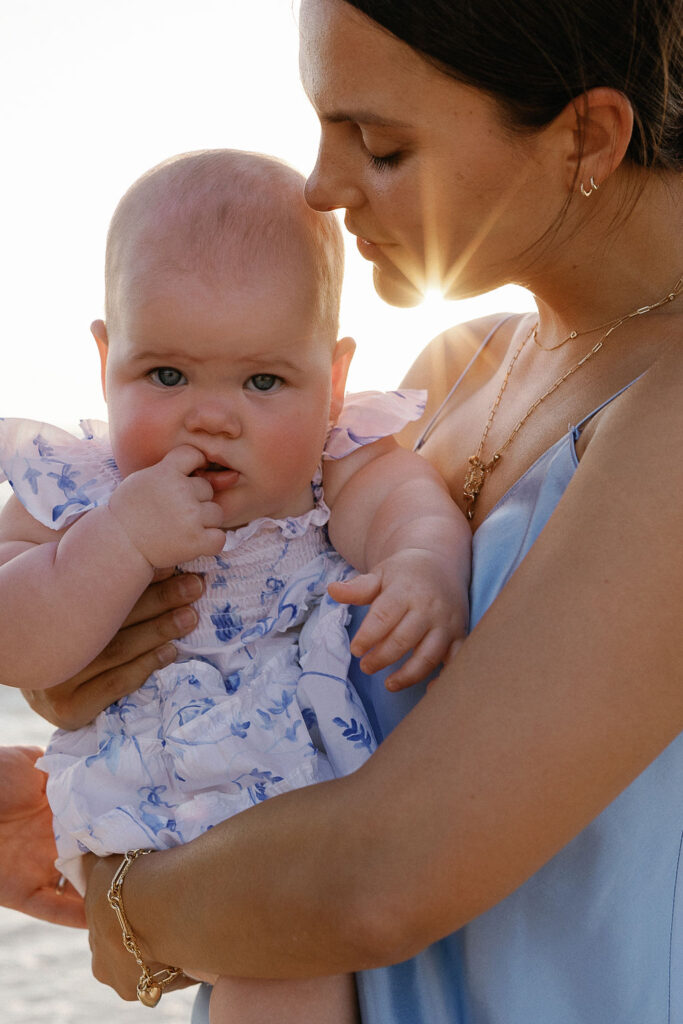 Mon cuddling baby on beach during Naples family photos, showcasing what to wear for family beach pictures.